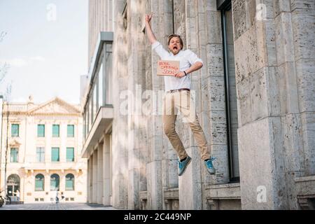 Aufgeregter Ladenbesitzer hält Pappe mit Eröffnungsansage in der Stadt Stockfoto