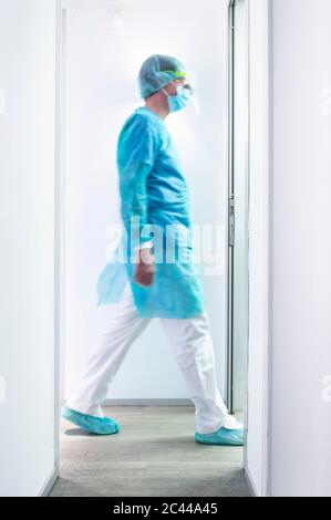 Reifer männlicher Zahnarzt, der in beleuchteten Flur in der Klinik geht Stockfoto