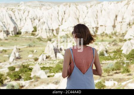 Ansicht der Rückseite des jungen Frau an der felsigen Landschaft suchen, während in Göreme, Kappadokien, Türkei Stockfoto