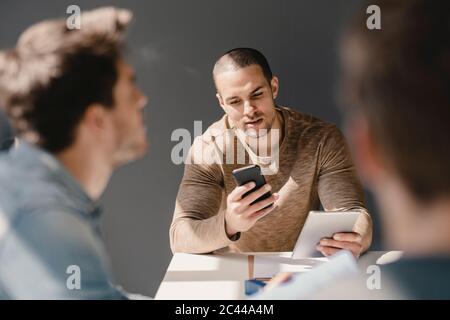 Jungunternehmer in einem Meeting mit Smartphone und digitalem Tablet Stockfoto