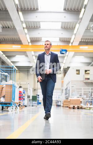 Reifer Geschäftsmann, der in einer Fabrik läuft Stockfoto