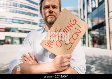 Ladenbesitzer hält Pappe mit Öffnungsansage in der Stadt Stockfoto