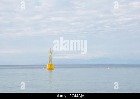 Gelbe Boje auf einem ruhigen Meer mit Himmel im Hintergrund, Leuchtfeuer auf dem Wasser, kopieren Raum. Meeresküste von Griechenland Meer früh am Morgen Stockfoto