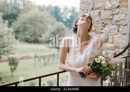 Junge lächelnde Frau in eleganten Brautkleid mit Blumenstrauß Stockfoto