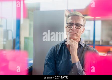 Nachdenklich reifen männlichen Unternehmer Blick auf Klebstoff Notizen auf Glas im Büro Stockfoto