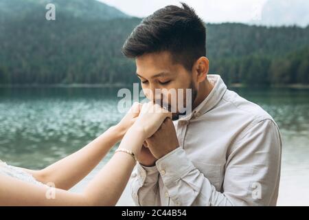 Kasachische Bräutigam küsst sanft die Hände seiner Braut Stockfoto