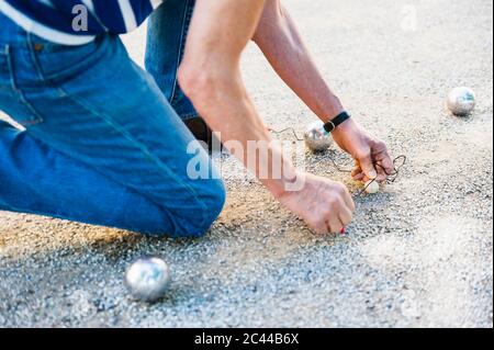 Crop-Ansicht der knieenden Boule Spieler messing Lücke zwischen den Kugeln Stockfoto