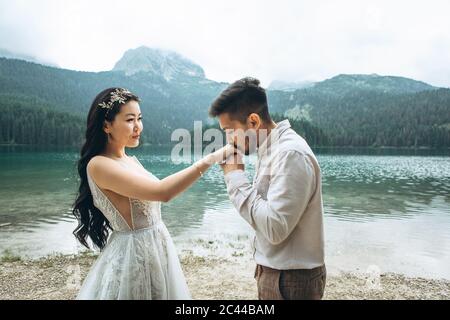 Kasachische Bräutigam küsst sanft die Hände seiner Braut Stockfoto