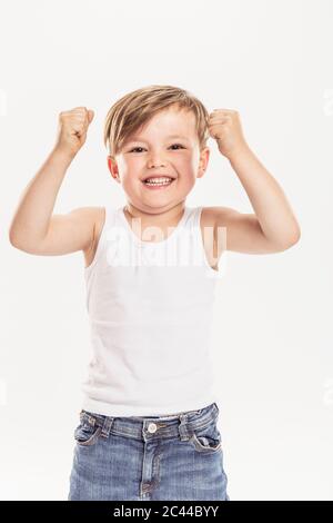 Porträt eines kleinen Jungen, der Fäuste zusammenhält, die vor weißem Hintergrund stehen Stockfoto