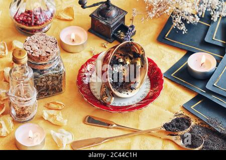 Vintage Teetase auf seiner Seite auf Wiccan Hexenaltar zum Lesen von Teeblättern als eine Methode der Weissagung, um die Zukunft vorherzusagen. Hellgelbes Tuch Stockfoto