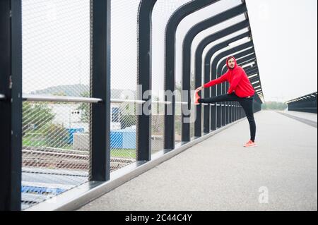 Junger Mann, der sich auf einer Brücke ausdehnt Stockfoto