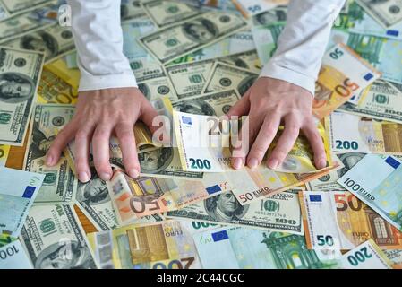 Weibliche Hände greifen nach einem Haufen Geld. Dollar- und Euro-Banknoten auf dem Tisch. Das Konzept von Reichtum, Erfolg, Gier und Korruption, Geldgier Stockfoto