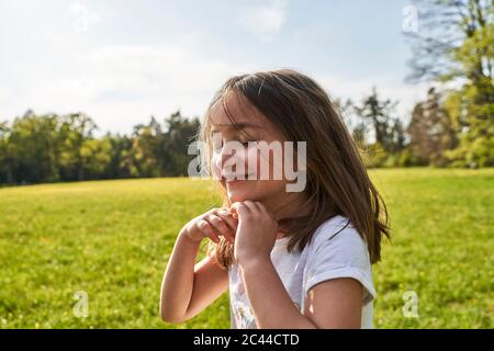 Nettes Mädchen mit geschlossenen Augen und zerzauste Haare gegen den Himmel an sonnigen Tag Stockfoto