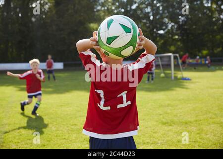 Fußball Junge werfen Ball auf dem Feld Stockfoto