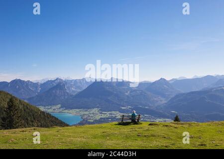 Ansicht der Rückseite des älteren männlichen Wanderer sitzt auf der Bank, während Sie am Dachstein gegen den blauen Himmel Stockfoto