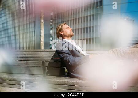 Geschäftsmann, der sich auf einer Bank in der Stadt entspannt Stockfoto