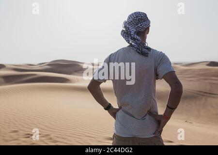 Männlicher Tourist, der auf Sanddünen in der Wüste in Dubai, Vereinigte Arabische Emirate steht Stockfoto