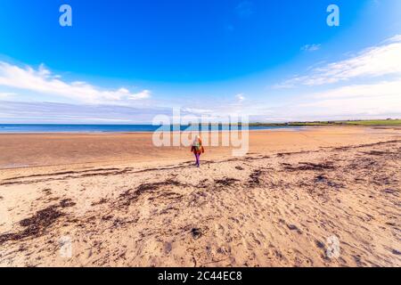 Schottland, Orkney Inseln, Süd Ronaldsay, Rückansicht der Frau, die in der Landschaft spazieren geht Stockfoto