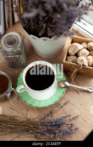 Bücher, Kaffee und ein Bouquet von getrocknetem Lavendel. Stillleben auf dem Tisch. Frühstück, Aussicht von oben. Eine Tasse belebenden Getränks. Startseite gemütlich Hintergrund. Stockfoto