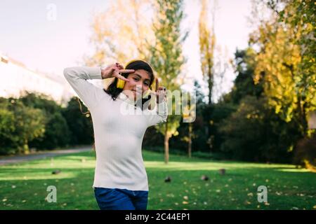 Mädchen, die Musik über Kopfhörer hören, die Friedenszeichen im Park zeigen Stockfoto