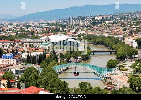 Friedensbrücke über den Fluss Kura gegen Stadtbild, Tiflis, Georgien Stockfoto