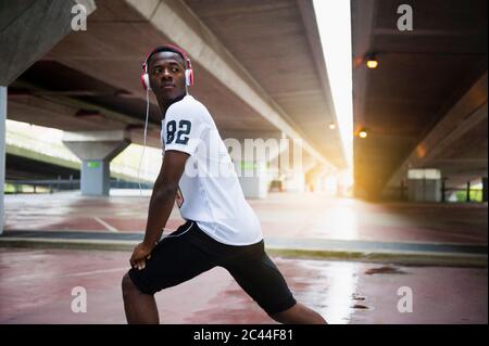 Junger Jogger, der sein Bein in der Stadt streckt Stockfoto