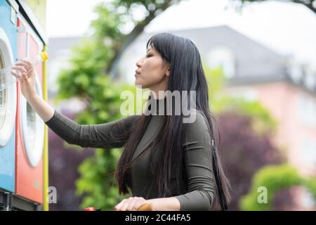 Frau wirft Flasche in Mülltonne Stockfoto
