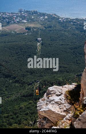 Seilbahn im Sommer. Die Seilbahn steigt vom Berg ab. Blick von den Bergen auf das Meer. Stockfoto