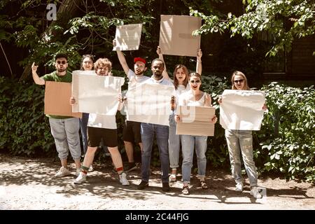 Diverse Gruppe von Menschen protestieren mit leerem Schild. Protest gegen Menschenrechte, Missbrauch von Freiheit, soziale Fragen, tatsächliche Probleme. Männer und Frauen auf der Straße sehen wütend aus, schreien. Copyspace. Stockfoto