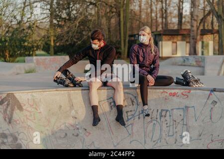 Junges Paar sitzt mit Inline-Skates im Skateboard Park Stockfoto