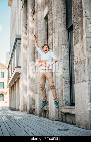 Aufgeregter Ladenbesitzer hält Pappe mit Eröffnungsansage in der Stadt Stockfoto