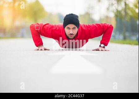 Junger Mann, der Liegestütze auf einer Fahrspur macht Stockfoto