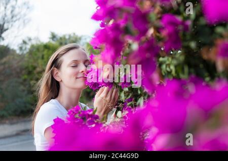 Porträt einer Frau mit geschlossenen Augen riechende lila Blüten, Sardinien, Italien Stockfoto