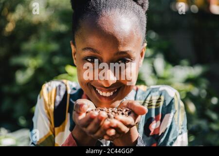 Porträt einer glücklichen jungen Frau, die geröstete Kaffeebohnen in den Händen hält Stockfoto