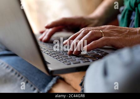 Reife Frau mit Laptop während der Arbeit zu Hause während Ausgangssperre Stockfoto