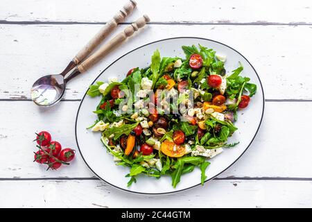 Teller mit kohlenhydratarmen vegetarischen Salat mit Rucola, Tomaten, Nüssen und Mozzarella-Käse Stockfoto