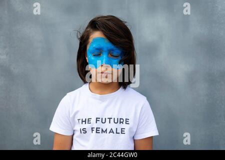 Porträt des Jungen mit bemalter blauer Maske auf seinem Gesicht trägt T-Shirt mit Aufdruck "die Zukunft ist weiblich" Stockfoto