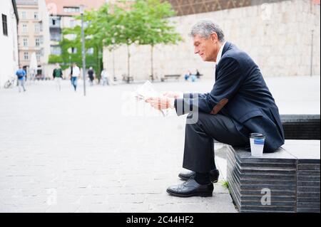 Senior Geschäftsmann liest Zeitung im Freien Stockfoto