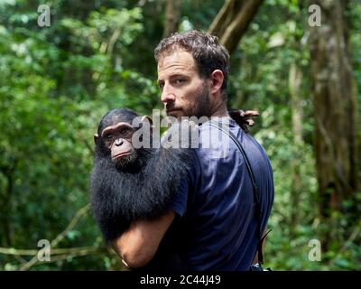 Kamerun, Pongo-Songo, Mann, der Schimpansen (Pan troglodytes) im Wald trägt Stockfoto