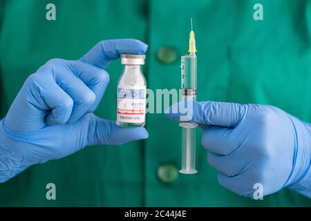 Frau in Schutzkleidung mit Covid-19-Impfstoff und Spritze Stockfoto