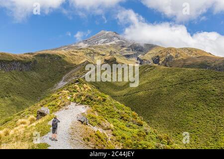 Neuseeland, männlicher Wanderer, der im Frühling die malerische Aussicht auf den Vulkan Mount Taranaki bewundert Stockfoto