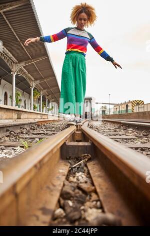 Ansicht der Oberfläche der jungen Frau, die auf Eisenbahnschienen gegen den Himmel geht Stockfoto