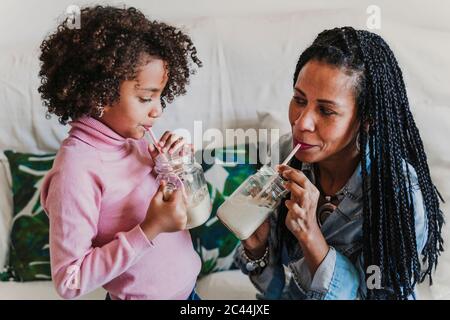 Mutter und ihre kleine Tochter trinken zu Hause Smoothies Stockfoto