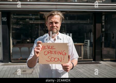 Ladenbesitzer hält Pappe mit Öffnungsansage in der Stadt Stockfoto