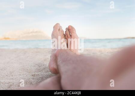Die Füße des Mannes sind sandig am Strand, Sardinien, Italien Stockfoto