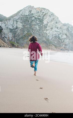 Junge Frau hinterlässt beim Laufen am Strand von Ursa, Region Lissabon, Portugal Stockfoto