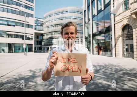 Ladenbesitzer hält Pappe mit Öffnungsansage in der Stadt Stockfoto