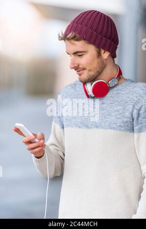 Stilvoller junger Mann mit Smartphone im Freien Stockfoto