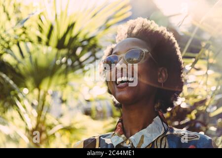 Porträt der glückliche junge Frau mit Sonnenbrille im Garten Stockfoto