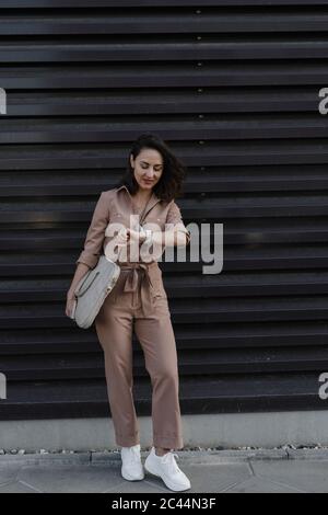 Geschäftsfrau Überprüfung Smart Uhr, während sie gegen schwarzen Verschluss stehen Stockfoto